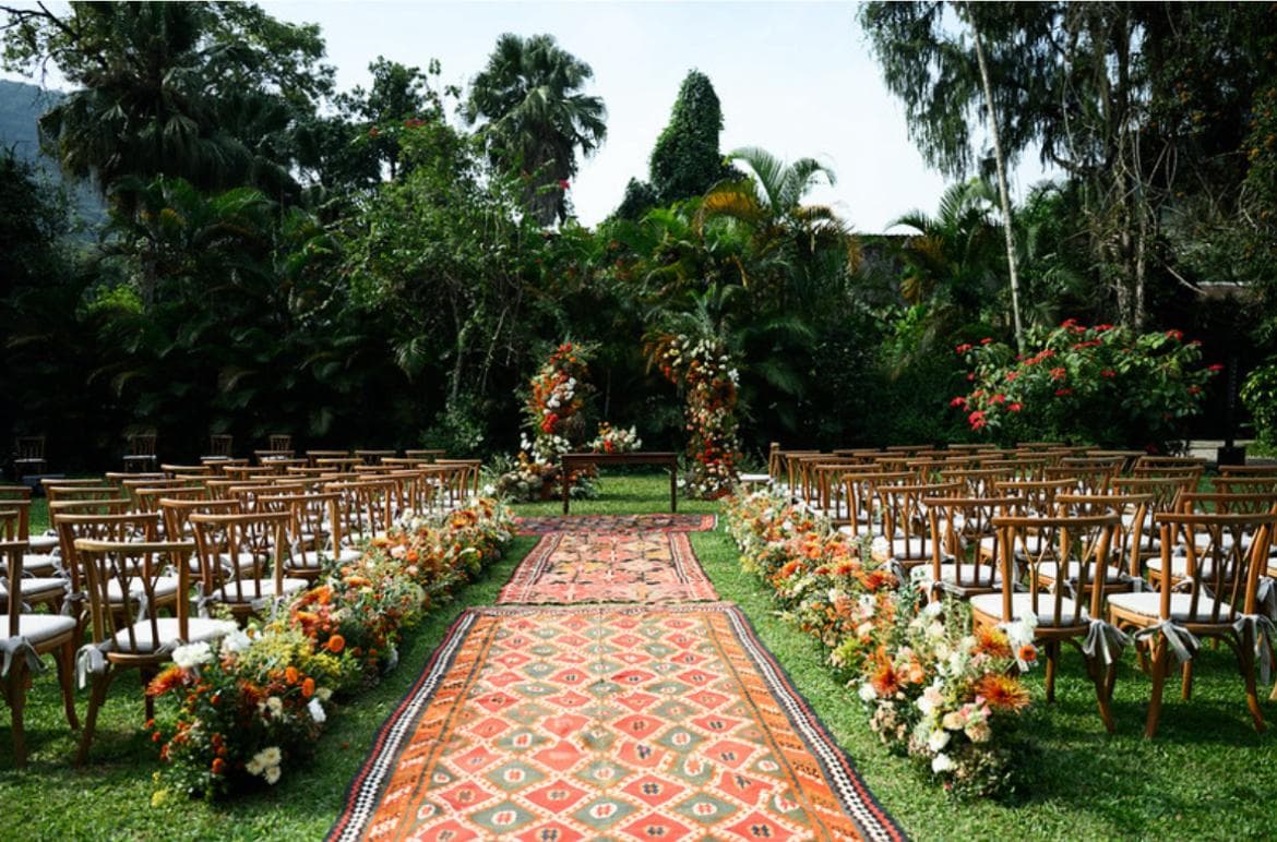Cerimônia ao ar livre decorada com tapetes e arcos florais