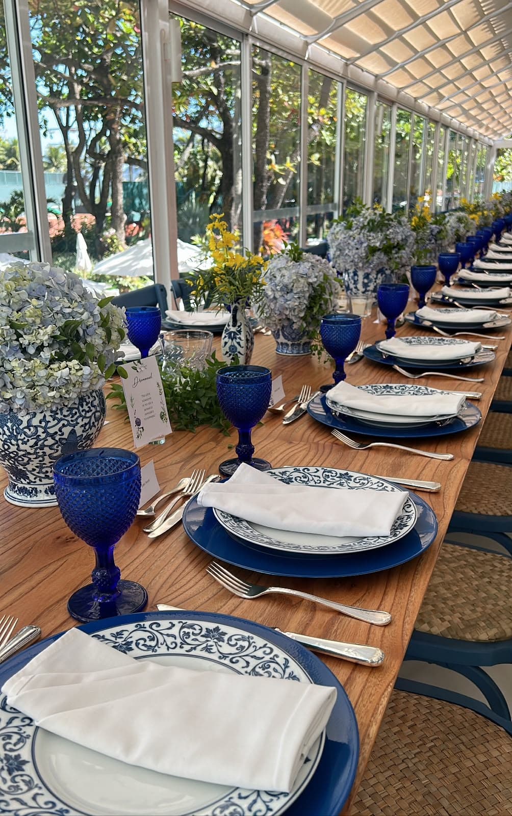 Mesa posta com louça azul e branca e taças de cristal azul