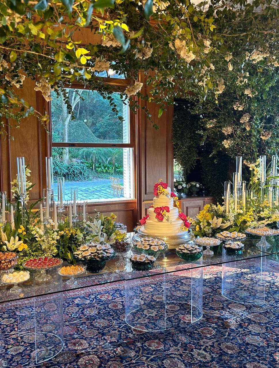 Mesa do bolo com decoração aérea de folhagem e flores