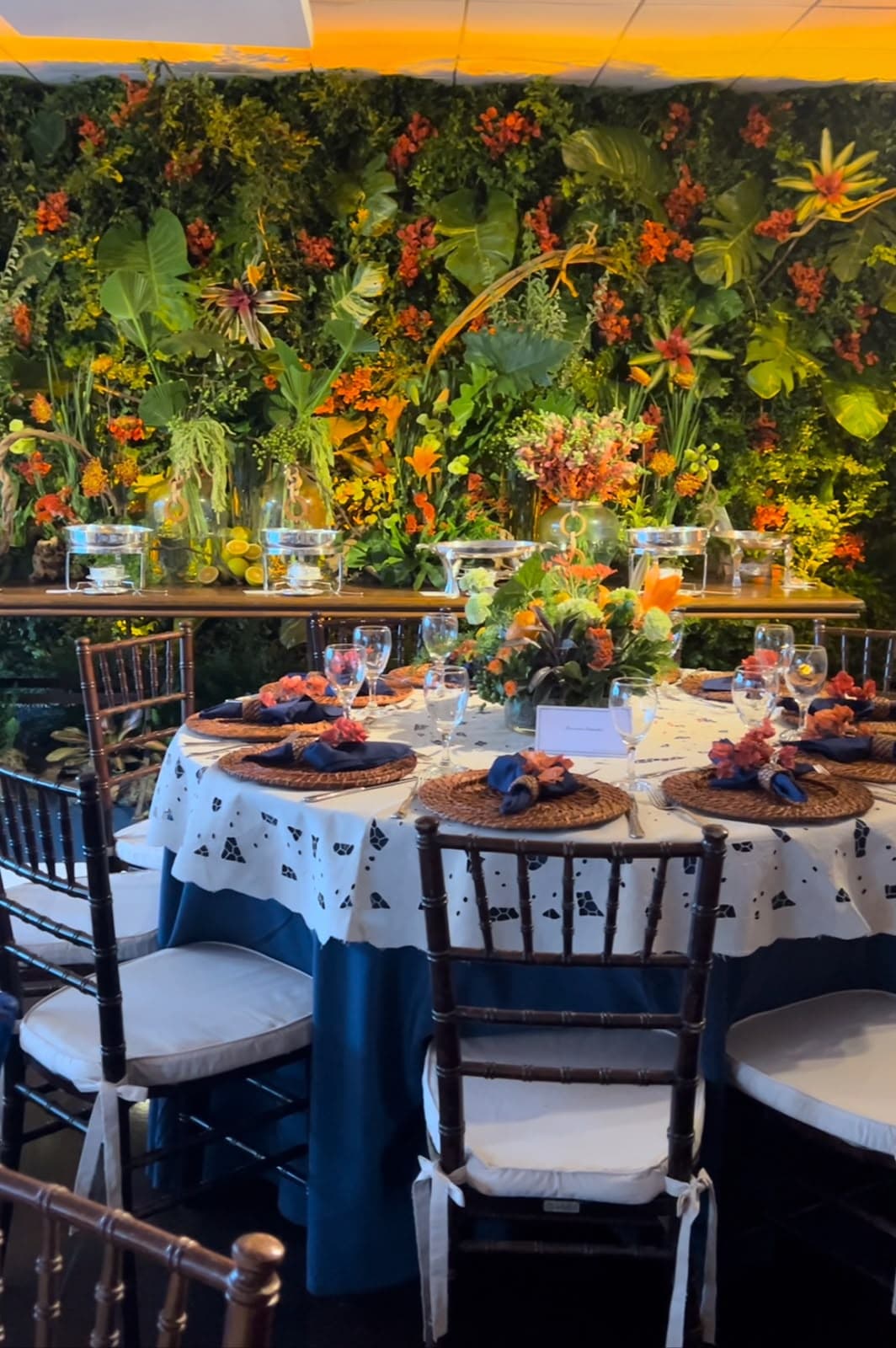 Mesa redonda diante de parede de folhagem e flores